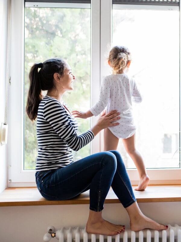 Mother and her daughter looking out of a window