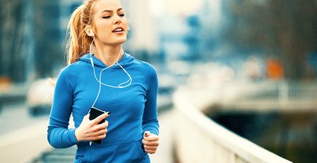 Woman running across a bridge while listening to music