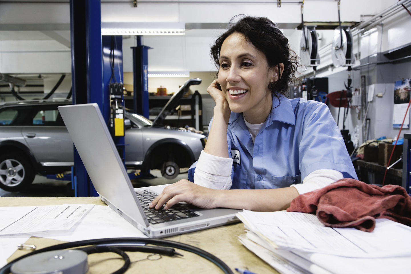 Female auto mechanic using laptop in auto repair shop