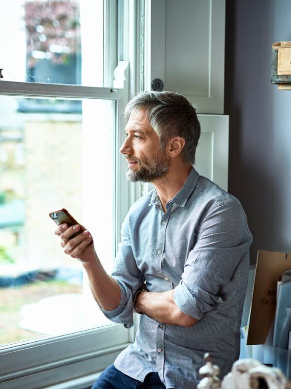 Man sat by a window texting