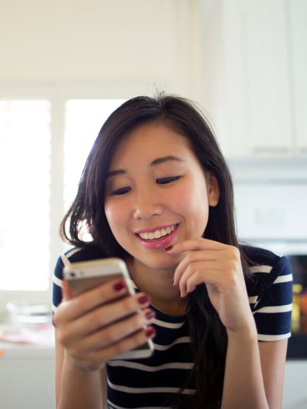 Young woman smiling at her mobile phone